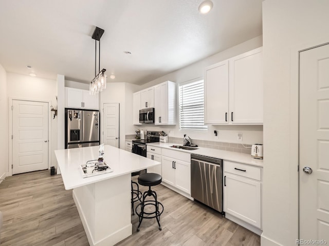 kitchen with white cabinetry, appliances with stainless steel finishes, a center island, and a breakfast bar area