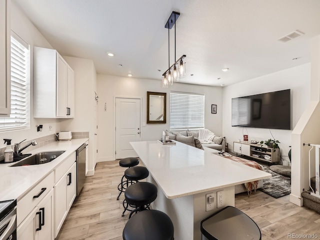 kitchen with light wood-type flooring, a center island, hanging light fixtures, and a kitchen bar