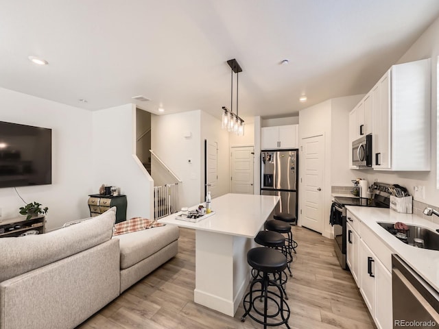 kitchen featuring a center island, white cabinets, pendant lighting, a breakfast bar, and stainless steel appliances