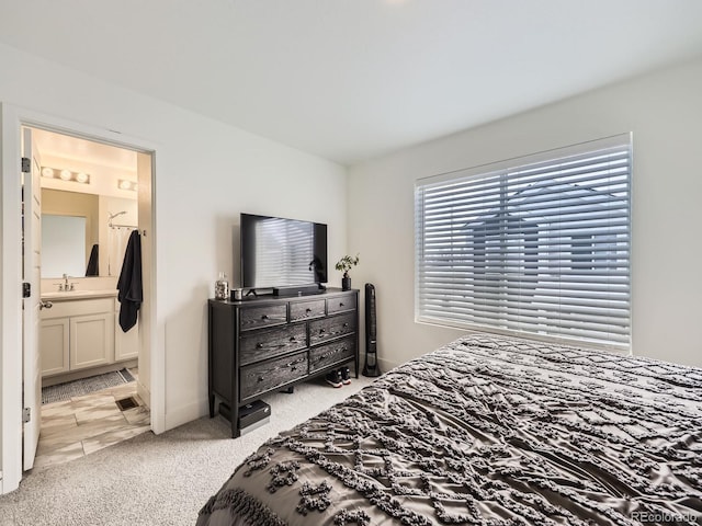 bedroom featuring light colored carpet, connected bathroom, and sink