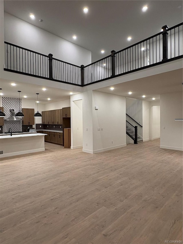 living room featuring a high ceiling, light hardwood / wood-style flooring, and sink