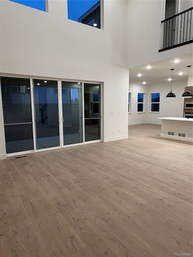 unfurnished living room with a towering ceiling and hardwood / wood-style flooring