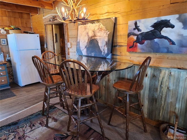 dining space featuring wooden walls, dark hardwood / wood-style flooring, and an inviting chandelier