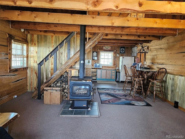 workout area with carpet flooring, a wood stove, and wooden walls