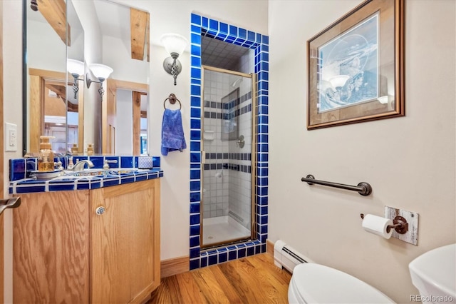 full bathroom with toilet, wood finished floors, a stall shower, a baseboard heating unit, and vanity
