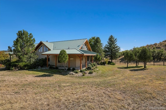 view of home's exterior with metal roof, fence, stucco siding, and a lawn