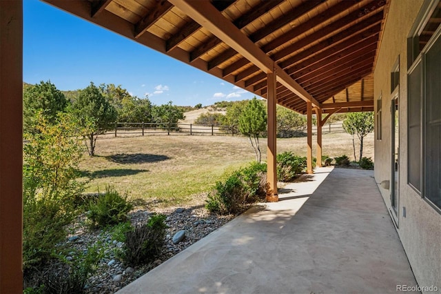 view of patio with fence and a rural view
