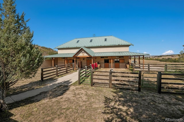 view of front facade featuring metal roof, an outdoor structure, a rural view, and an exterior structure