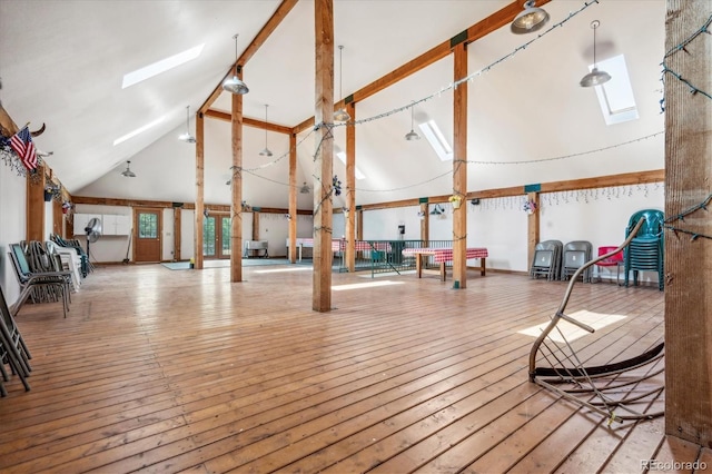 interior space featuring a skylight, wood-type flooring, and high vaulted ceiling