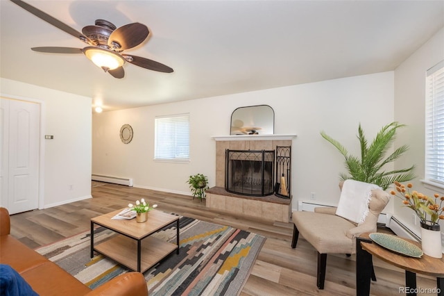 living room with a fireplace, a baseboard radiator, light hardwood / wood-style flooring, and ceiling fan