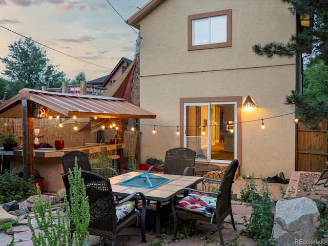 109 Bear Creek Ln, Morrison, CO 80465 - back of house at dusk with outdoor dining area, a patio, and stucco siding