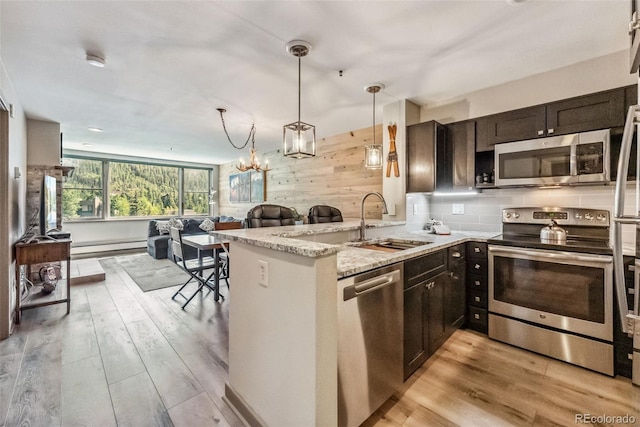 kitchen featuring appliances with stainless steel finishes, light wood-type flooring, sink, and a notable chandelier