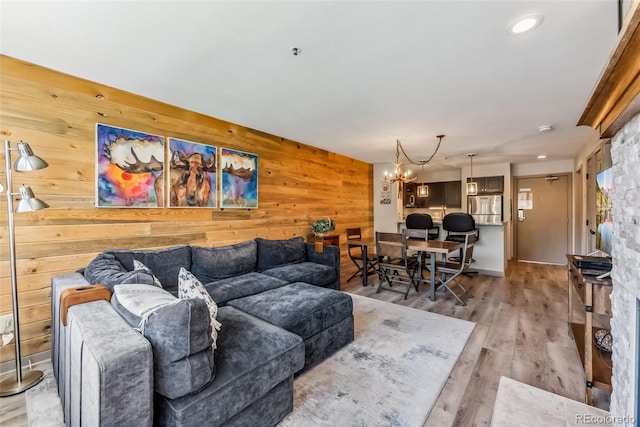 living room featuring wooden walls, light hardwood / wood-style flooring, and a notable chandelier