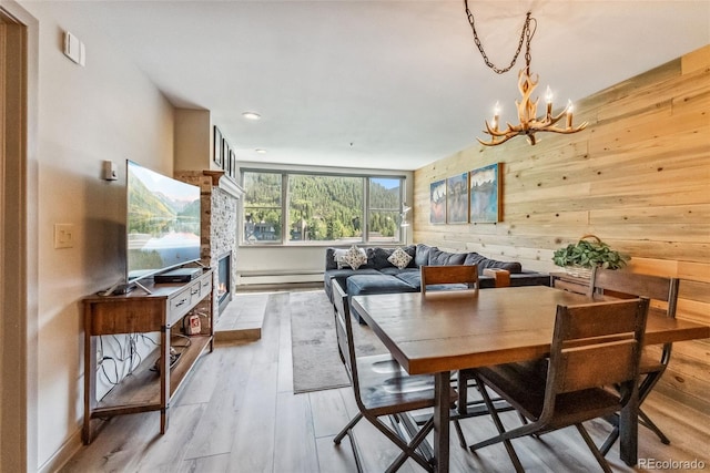 dining area featuring light hardwood / wood-style flooring, wooden walls, a chandelier, and baseboard heating