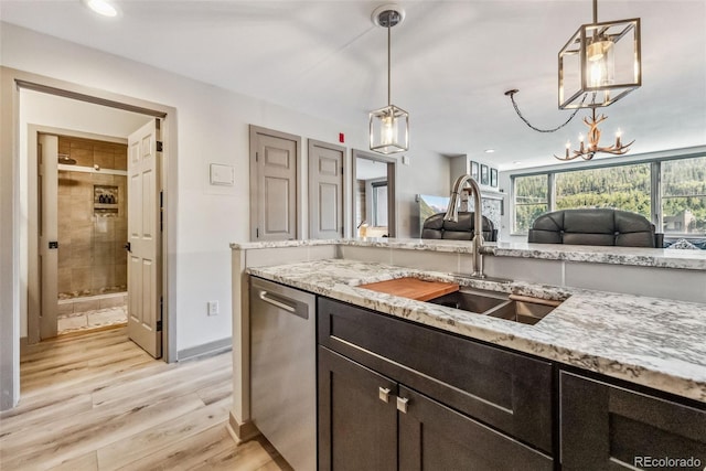 kitchen with light stone counters, sink, decorative light fixtures, dishwasher, and light hardwood / wood-style floors