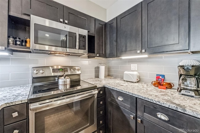 22174 US Highway 6 Unit 1535, Dillon, CO 80435 - kitchen with dark cabinetry, decorative backsplash, light stone counters, and appliances with stainless steel finishes