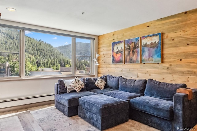 living room featuring wooden walls, light hardwood / wood-style flooring, a mountain view, and a baseboard radiator