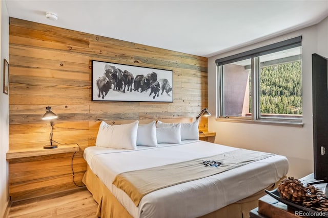 bedroom featuring light wood-type flooring and wooden walls