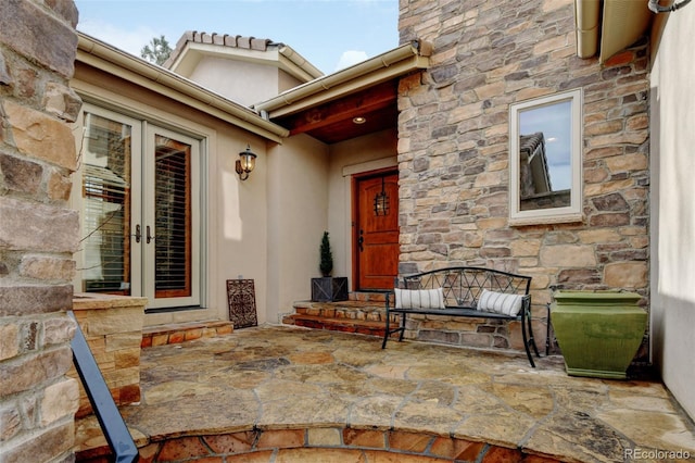 doorway to property featuring stone siding, french doors, and a patio area