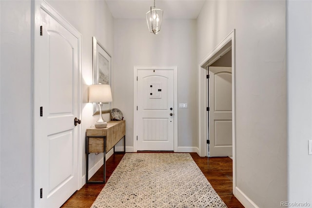 entryway featuring an inviting chandelier, baseboards, and dark wood finished floors