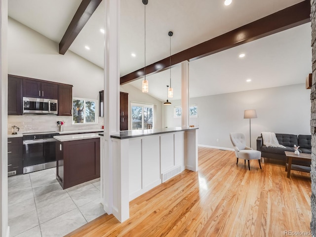 kitchen with appliances with stainless steel finishes, vaulted ceiling with beams, dark brown cabinetry, decorative light fixtures, and kitchen peninsula