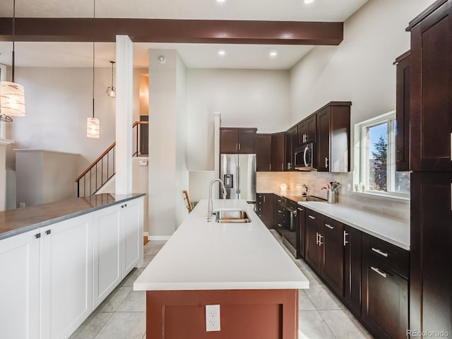 kitchen featuring sink, hanging light fixtures, a center island with sink, appliances with stainless steel finishes, and beam ceiling