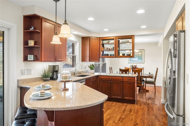 kitchen featuring a peninsula, a breakfast bar, decorative light fixtures, and freestanding refrigerator