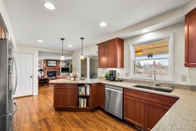 kitchen featuring pendant lighting, open shelves, appliances with stainless steel finishes, a sink, and a peninsula