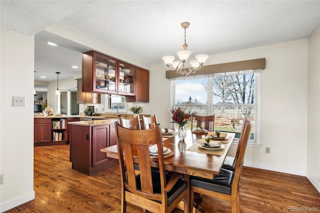 dining space with baseboards, a textured ceiling, a chandelier, and dark wood-type flooring