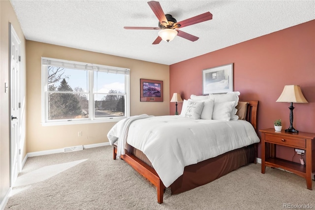 bedroom featuring visible vents, light colored carpet, and a textured ceiling