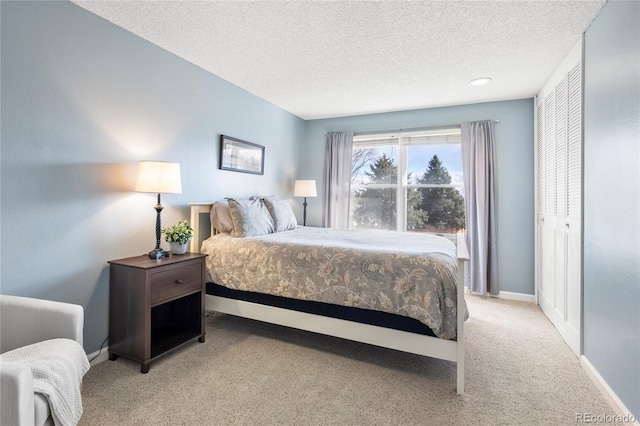 bedroom with baseboards, a textured ceiling, and light colored carpet