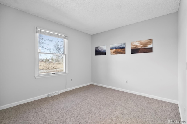 carpeted spare room featuring a textured ceiling, visible vents, and baseboards