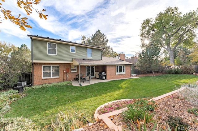 back of property featuring brick siding, a yard, a chimney, a patio area, and fence