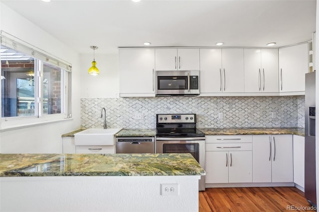 kitchen featuring white cabinetry, sink, hanging light fixtures, and appliances with stainless steel finishes