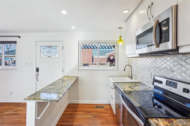 kitchen with pendant lighting, sink, stainless steel appliances, and dark wood-type flooring