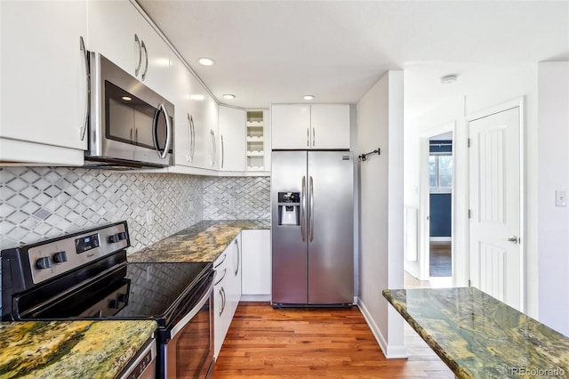 kitchen featuring white cabinets, appliances with stainless steel finishes, backsplash, and dark stone countertops