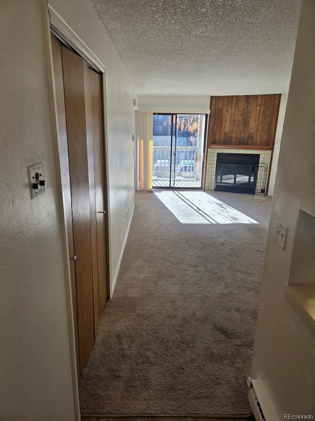 unfurnished living room featuring wooden walls, a textured ceiling, baseboard heating, and carpet flooring