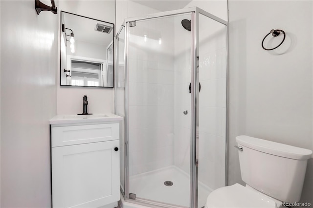 bathroom featuring vanity, a shower with shower door, and toilet