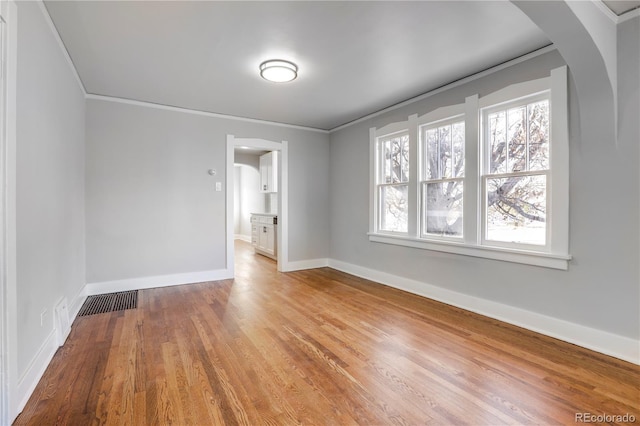 empty room with crown molding and light hardwood / wood-style floors