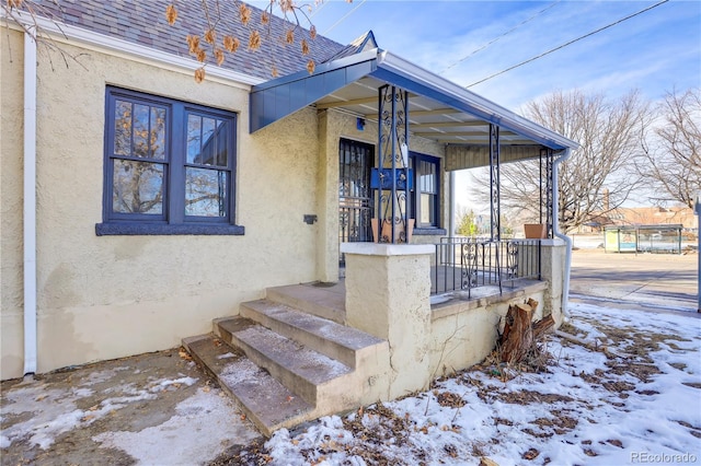 snow covered property entrance with covered porch