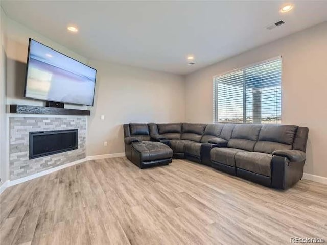 living room featuring a stone fireplace and light hardwood / wood-style floors