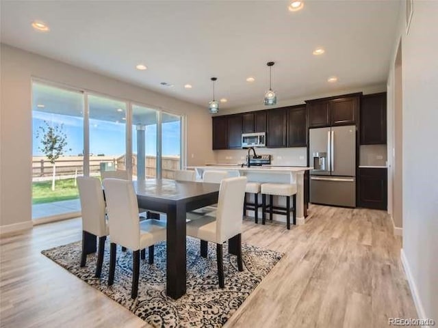 dining space with light hardwood / wood-style flooring, sink, and a wealth of natural light