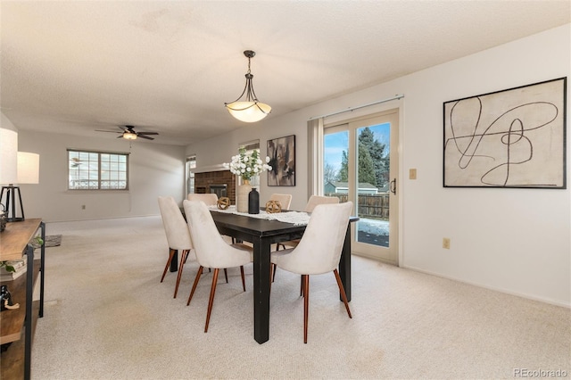 dining space featuring a brick fireplace, light colored carpet, ceiling fan, and a wealth of natural light