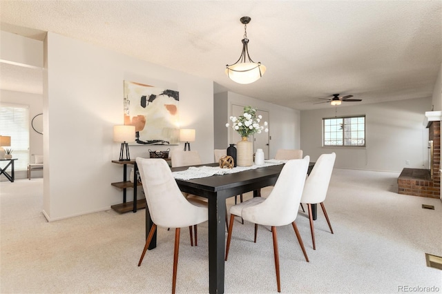 dining area with light colored carpet, ceiling fan, and a textured ceiling