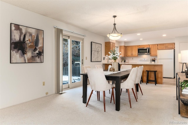 dining area featuring light colored carpet, a textured ceiling, and a healthy amount of sunlight