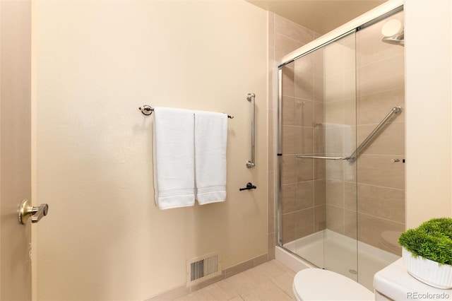 bathroom featuring toilet, an enclosed shower, and tile patterned flooring