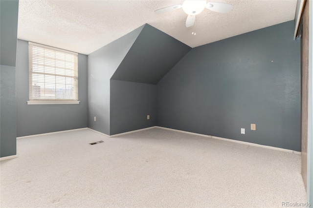 additional living space featuring vaulted ceiling, a textured ceiling, ceiling fan, and carpet