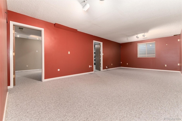 spare room featuring track lighting, carpet flooring, and a textured ceiling