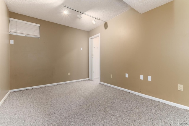 spare room featuring track lighting, a textured ceiling, and carpet