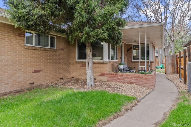 view of front facade featuring brick siding, crawl space, fence, and a front yard
